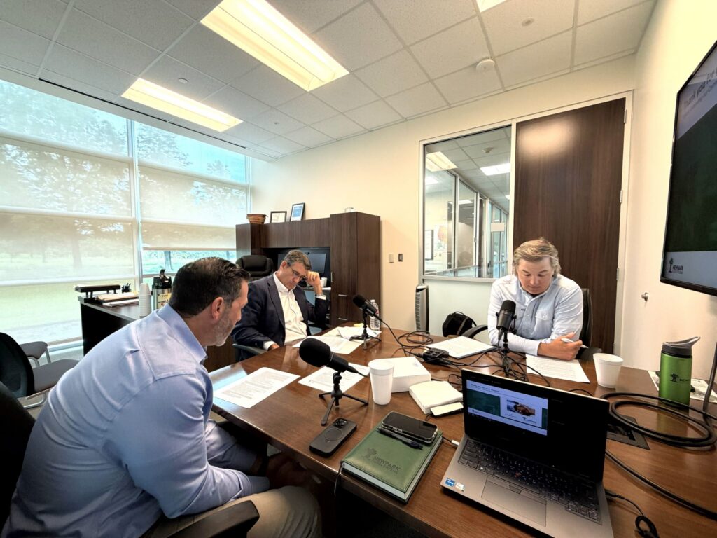 Three men recording a podcast episode in an office environment.